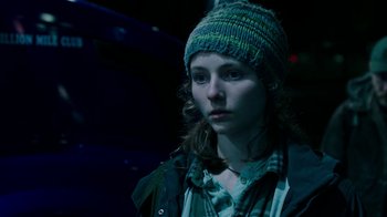 Movie still from “Leave No Trace” (2018), directed by Debra Granik – A young woman wearing a hat and a plaid shirt; Close Up shot, Over the shoulder angle