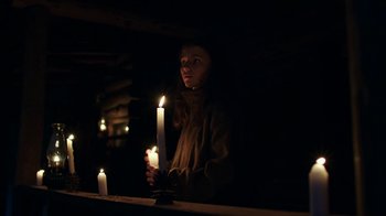 Movie still from “Leave No Trace” (2018), directed by Debra Granik – A woman holding a candle in a dark room; Medium shot, Low angle
