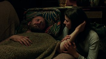Movie still from “Leave No Trace” (2018), directed by Debra Granik – A man and a woman laying in a bed together; Medium shot, High angle