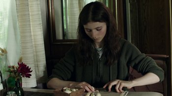 Movie still from “Leave No Trace” (2018), directed by Debra Granik – A woman sitting at a table cutting mushrooms; Medium shot, Over the shoulder angle