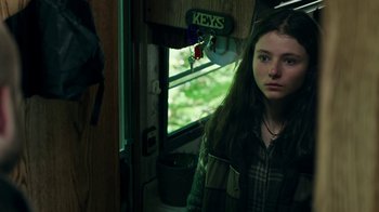 Movie still from “Leave No Trace” (2018), directed by Debra Granik – A young woman standing in a room next to a window; Close Up shot, High angle