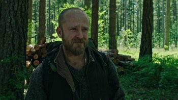 Movie still from “Leave No Trace” (2018), directed by Debra Granik – A man with a beard wearing a vest and a backpack; Close Up shot, Low angle