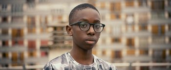 A young man wearing glasses in front of a building