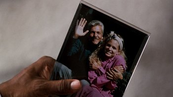 Movie still from “Lethal Weapon” (1987), directed by Richard Donner – A man holding a picture of a man and a woman; Extreme Close Up shot, Overhead angle