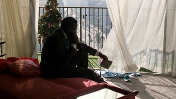 Movie still from “Lethal Weapon” (1987), directed by Richard Donner – A man sitting on top of a red couch talking on a phone; Wide shot, High angle