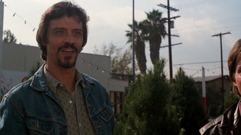 Movie still from “Lethal Weapon” (1987), directed by Richard Donner – A person wearing a jean jacket near trees; Close Up shot, Low angle