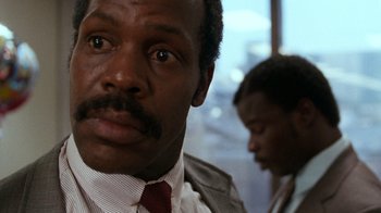 Movie still from “Lethal Weapon” (1987), directed by Richard Donner – A man in a suit and tie looking at the camera; Close Up shot, Low angle