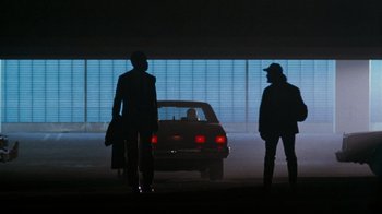 Movie still from “Lethal Weapon” (1987), directed by Richard Donner – Two people standing next to a car in a parking lot; Wide shot, Low angle