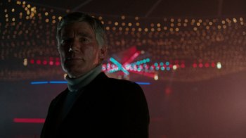 Movie still from “Lethal Weapon” (1987), directed by Richard Donner – A man standing in a room with lights in the background; Medium shot, Low angle