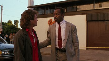 Movie still from “Lethal Weapon” (1987), directed by Richard Donner – A man in a business suit and a man in a red tie; Medium shot, Over the shoulder angle