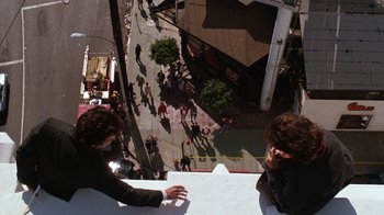 Movie still from “Lethal Weapon” (1987), directed by Richard Donner – Two people are standing on the side of a building talking; Extreme Wide shot, Overhead angle