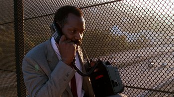 Movie still from “Lethal Weapon” (1987), directed by Richard Donner – A man talking on a cell phone while holding a briefcase; Close Up shot, Low angle