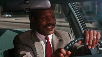 Movie still from “Lethal Weapon” (1987), directed by Richard Donner – A man in a suit and tie driving a car; Close Up shot, Low angle