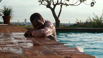 Movie still from “Lethal Weapon” (1987), directed by Richard Donner – A man leaning on a wall near a pool; Medium shot, High angle