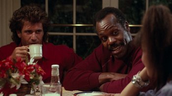 Movie still from “Lethal Weapon” (1987), directed by Richard Donner – A man sitting at a table in front of another man; Close Up shot, Over the shoulder angle