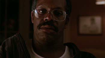 Movie still from “Lethal Weapon” (1987), directed by Richard Donner – A person wearing glasses with a mustache; Close Up shot, Low angle