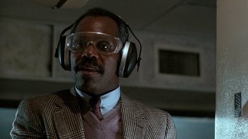 Movie still from “Lethal Weapon” (1987), directed by Richard Donner – A man wearing a suit and ear muffs; Close Up shot, Low angle