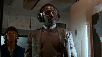 Movie still from “Lethal Weapon” (1987), directed by Richard Donner – A man wearing headphones and a jacket; Close Up shot, Low angle