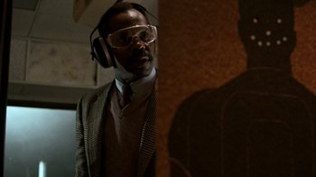 Movie still from “Lethal Weapon” (1987), directed by Richard Donner – A man wearing a suit and wearing ear muffs; Close Up shot, Low angle