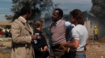 Movie still from “Lethal Weapon” (1987), directed by Richard Donner – A group of men standing next to each other on a street; Medium shot, Over the shoulder angle
