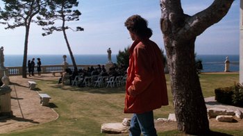 Movie still from “Lethal Weapon” (1987), directed by Richard Donner – A woman in a red jacket standing next to a tree; Wide shot, Over the shoulder angle