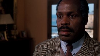 Movie still from “Lethal Weapon” (1987), directed by Richard Donner – A person wearing a suit and tie; Close Up shot, Low angle