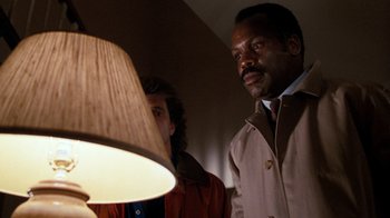 Movie still from “Lethal Weapon” (1987), directed by Richard Donner – A man standing next to a woman in front of a lamp; Close Up shot, Low angle