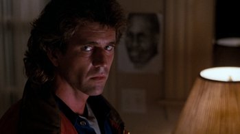 Movie still from “Lethal Weapon” (1987), directed by Richard Donner – A person wearing a jacket looking at a mirror; Close Up shot, Low angle