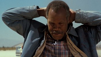 Movie still from “Lethal Weapon” (1987), directed by Richard Donner – An older man is holding his hands behind his head; Close Up shot, Low angle