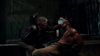 Movie still from “Lethal Weapon” (1987), directed by Richard Donner – A man is getting his face waxed by another man; Medium shot, Over the shoulder angle