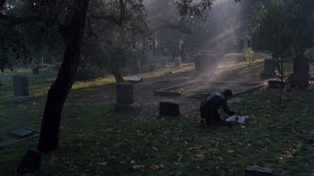 Movie still from “Lethal Weapon” (1987), directed by Richard Donner – A man sitting on the ground in a cemetery; Extreme Wide shot, High angle
