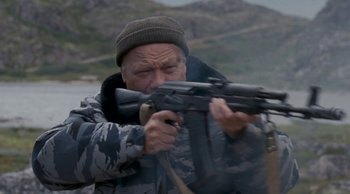 Movie still from “Leviathan” (2014), directed by Andrey Zvyagintsev – An older man holding a gun while standing next to a body of water; Medium shot, Low angle