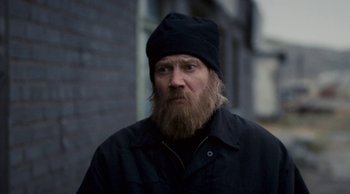 Movie still from “Leviathan” (2014), directed by Andrey Zvyagintsev – A man with a long beard wearing a black hat; Close Up shot, Over the shoulder angle