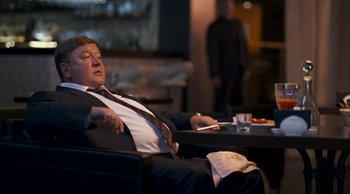 Movie still from “Leviathan” (2014), directed by Andrey Zvyagintsev – A man in a suit and tie sleeping in a chair; Medium shot, Low angle