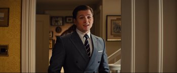 Movie still from “Kingsman: The Golden Circle” (2017), directed by Matthew Vaughn – A man wearing a suit and tie standing in a room; Medium shot, Over the shoulder angle