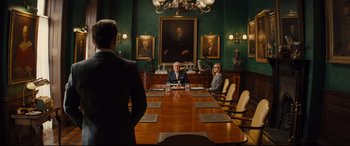 Movie still from “Kingsman: The Golden Circle” (2017), directed by Matthew Vaughn – A man and a woman sitting at a table in front of a painting; Wide shot, Over the shoulder angle