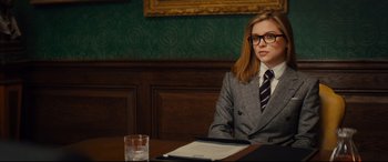 Movie still from “Kingsman: The Golden Circle” (2017), directed by Matthew Vaughn – A woman sitting at a table in front of a glass of water; Medium shot, Over the shoulder angle