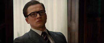 Movie still from “Kingsman: The Golden Circle” (2017), directed by Matthew Vaughn – A man in a suit and tie wearing glasses; Close Up shot, Low angle