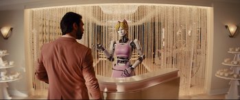 Movie still from “Kingsman: The Golden Circle” (2017), directed by Matthew Vaughn – A man standing next to a robot in a room; Wide shot, Over the shoulder angle