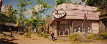 Movie still from “Kingsman: The Golden Circle” (2017), directed by Matthew Vaughn – A man standing in front of a building with plants; Wide shot, High angle