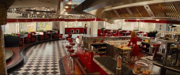 Movie still from “Kingsman: The Golden Circle” (2017), directed by Matthew Vaughn – A restaurant kitchen with red stools and checkerboard floor; Extreme Wide shot, High angle