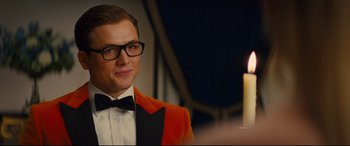 Movie still from “Kingsman: The Golden Circle” (2017), directed by Matthew Vaughn – A man wearing a bow tie and a red jacket; Close Up shot, Over the shoulder angle