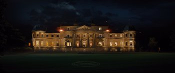 Movie still from “Kingsman: The Golden Circle” (2017), directed by Matthew Vaughn – A large building lit up at night with lights on it; Extreme Wide shot, High angle