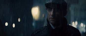 Movie still from “Kingsman: The Golden Circle” (2017), directed by Matthew Vaughn – A man with glasses and a hat is standing in the rain; Close Up shot, Low angle
