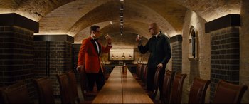 Movie still from “Kingsman: The Golden Circle” (2017), directed by Matthew Vaughn – Two men are drinking wine in a wine cellar; Wide shot, Over the shoulder angle
