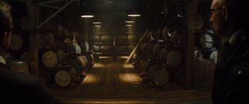 Movie still from “Kingsman: The Golden Circle” (2017), directed by Matthew Vaughn – A man standing in front of a room filled with barrels; Wide shot, High angle