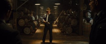 Movie still from “Kingsman: The Golden Circle” (2017), directed by Matthew Vaughn – A man standing in a room filled with barrels of alcohol; Wide shot, Low angle
