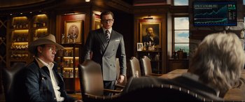 Movie still from “Kingsman: The Golden Circle” (2017), directed by Matthew Vaughn – A man in a suit standing in front of a table; Medium shot, Over the shoulder angle