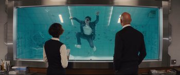 Movie still from “Kingsman: The Golden Circle” (2017), directed by Matthew Vaughn – Two people watching a man swimming in a swimming pool; Wide shot, Over the shoulder angle