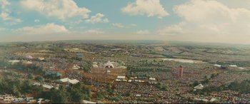 Movie still from “Kingsman: The Golden Circle” (2017), directed by Matthew Vaughn – An aerial view of an outdoor festival with tents and a crowd of people; Extreme Wide shot, High angle